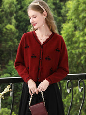 A woman wearing a red knit cardigan with embroidery.