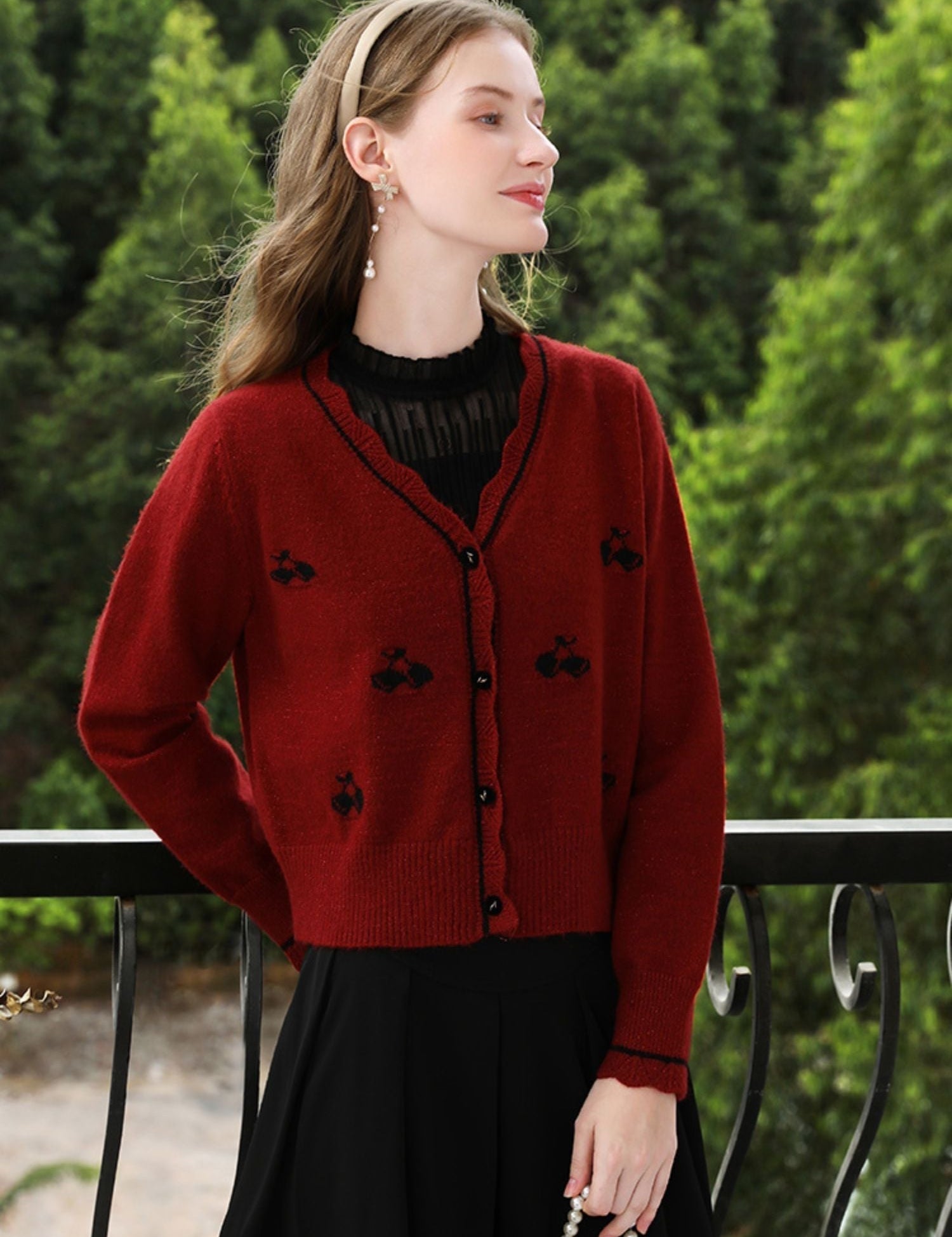 A woman wearing a red knit cardigan with embroidery.