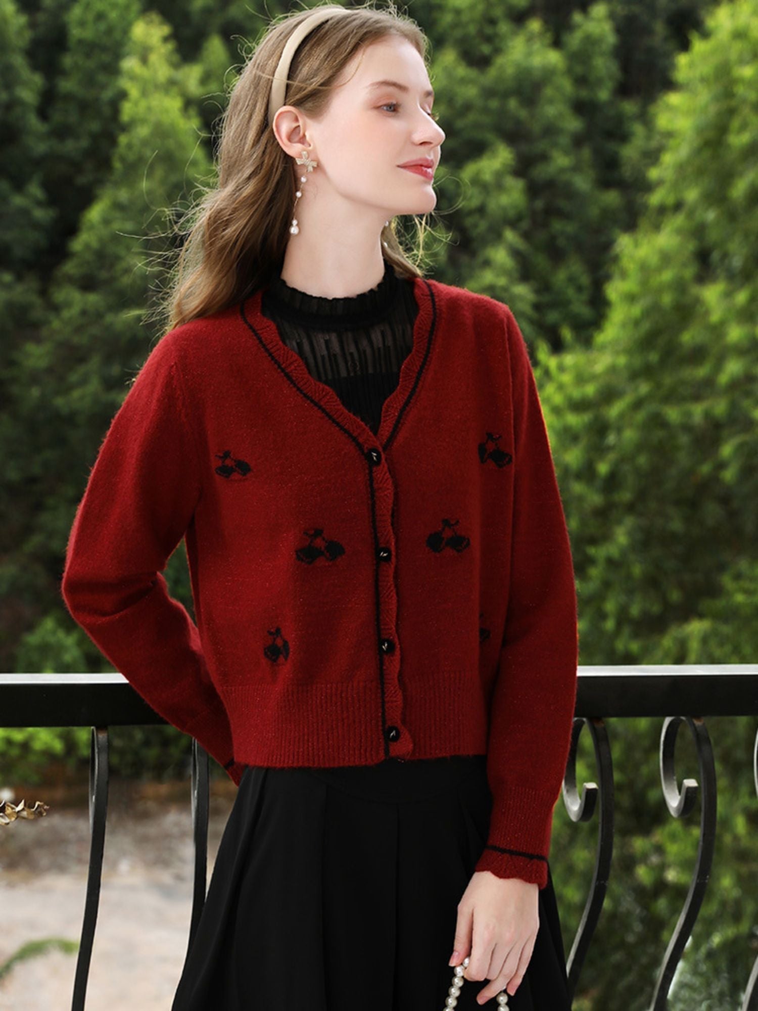 A woman wearing a red knit cardigan with embroidery.