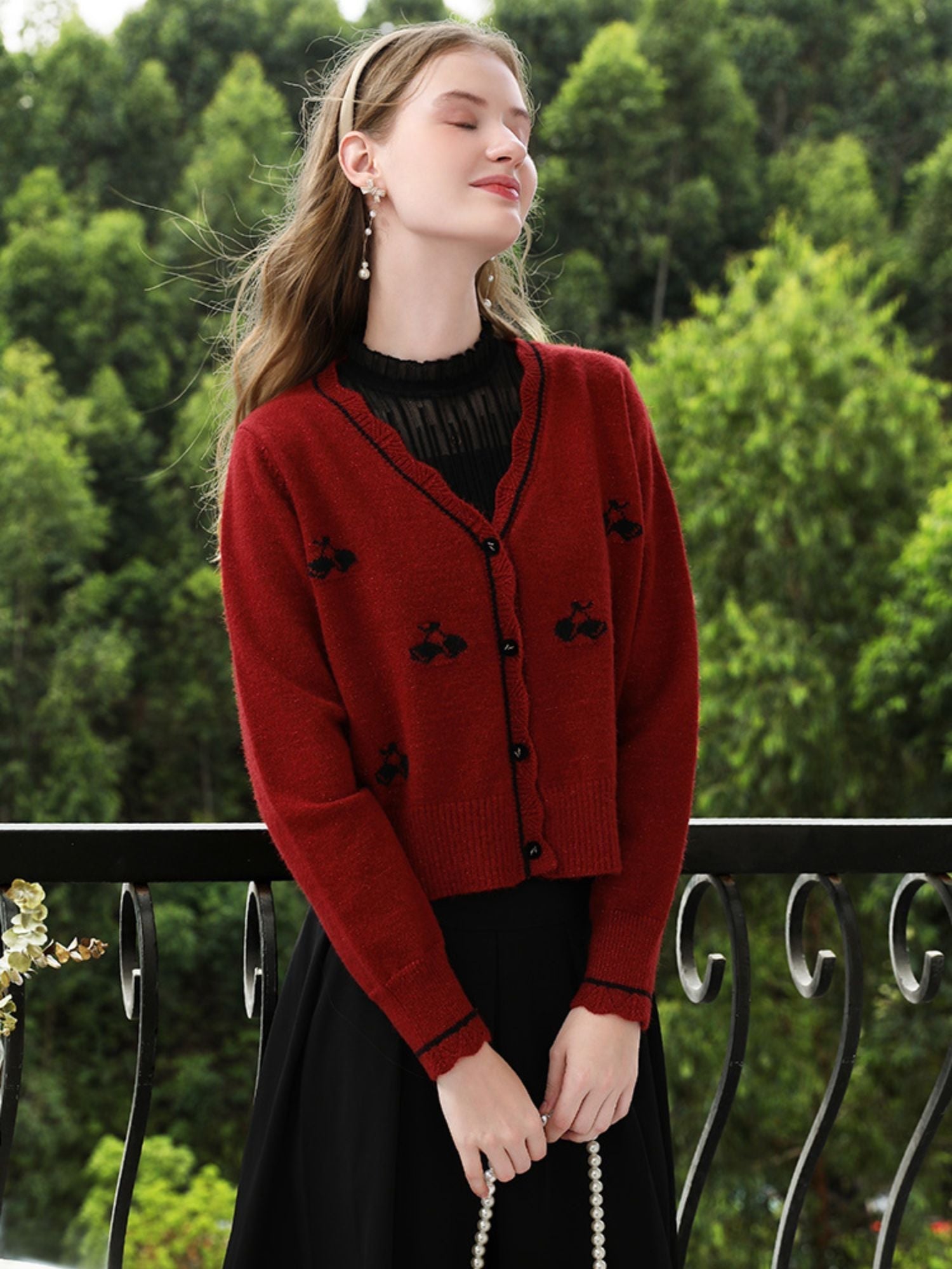 A woman wearing a red knit cardigan with embroidery.