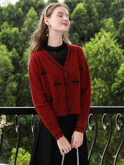 A woman wearing a red knit cardigan with embroidery.