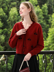 A woman wearing a red knit cardigan with embroidery.