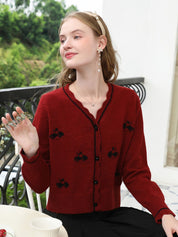 A woman wearing a red knit cardigan with embroidery.