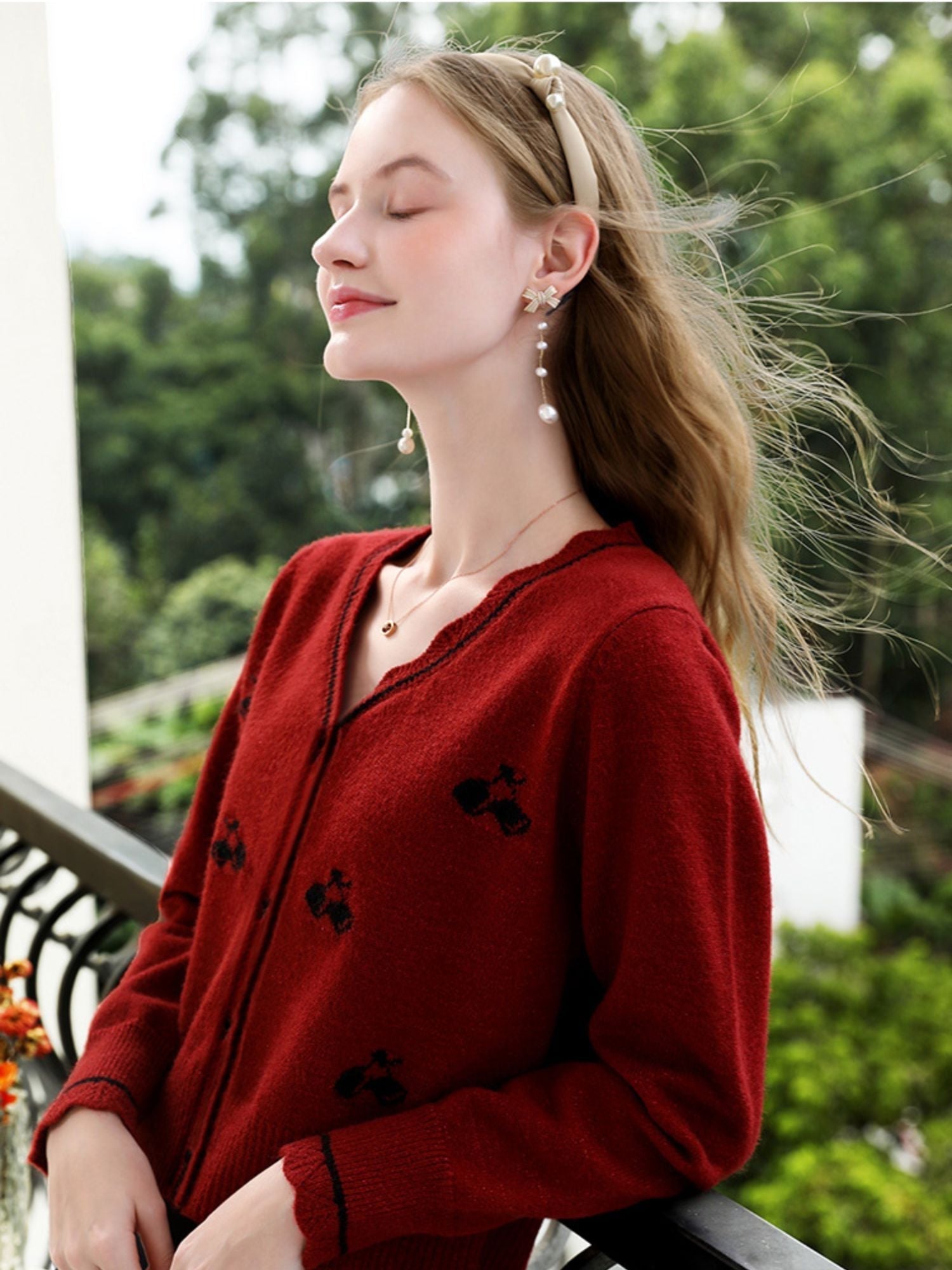 A woman wearing a red knit cardigan with embroidery.