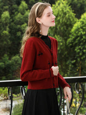A woman wearing a red knit cardigan with embroidery.