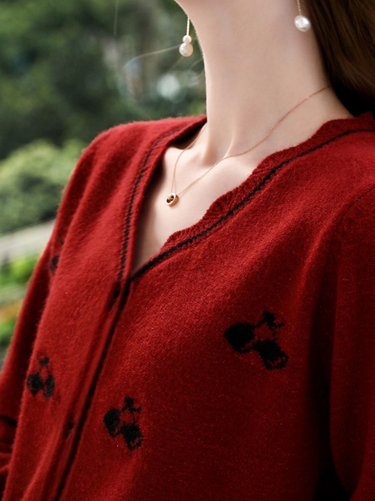 A woman wearing a red knit cardigan with embroidery.